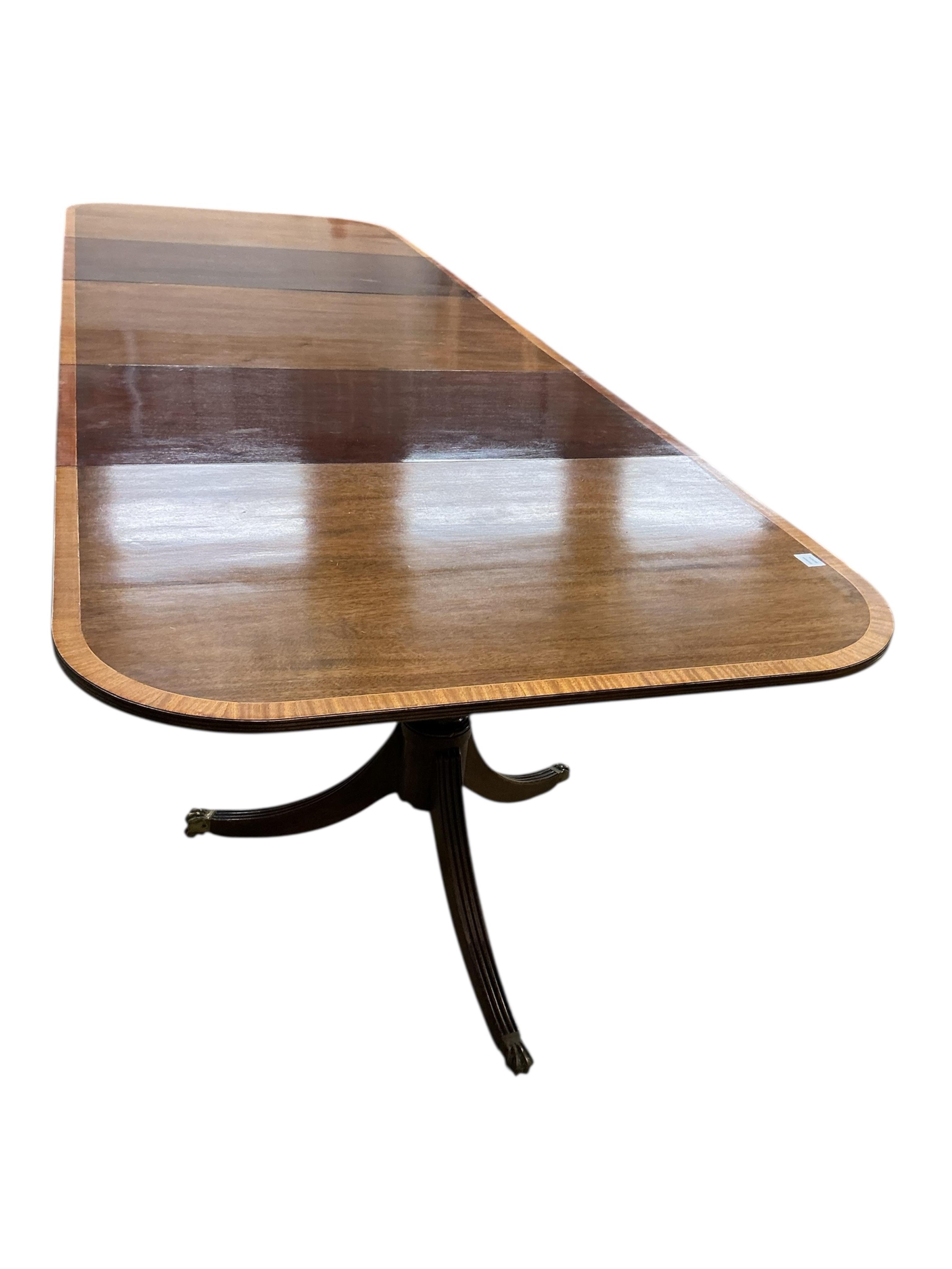 A Regency style mahogany and satinwood banded three pillar dining table, width 320cm extended, two spare leaves, depth 114cm, height 74cm